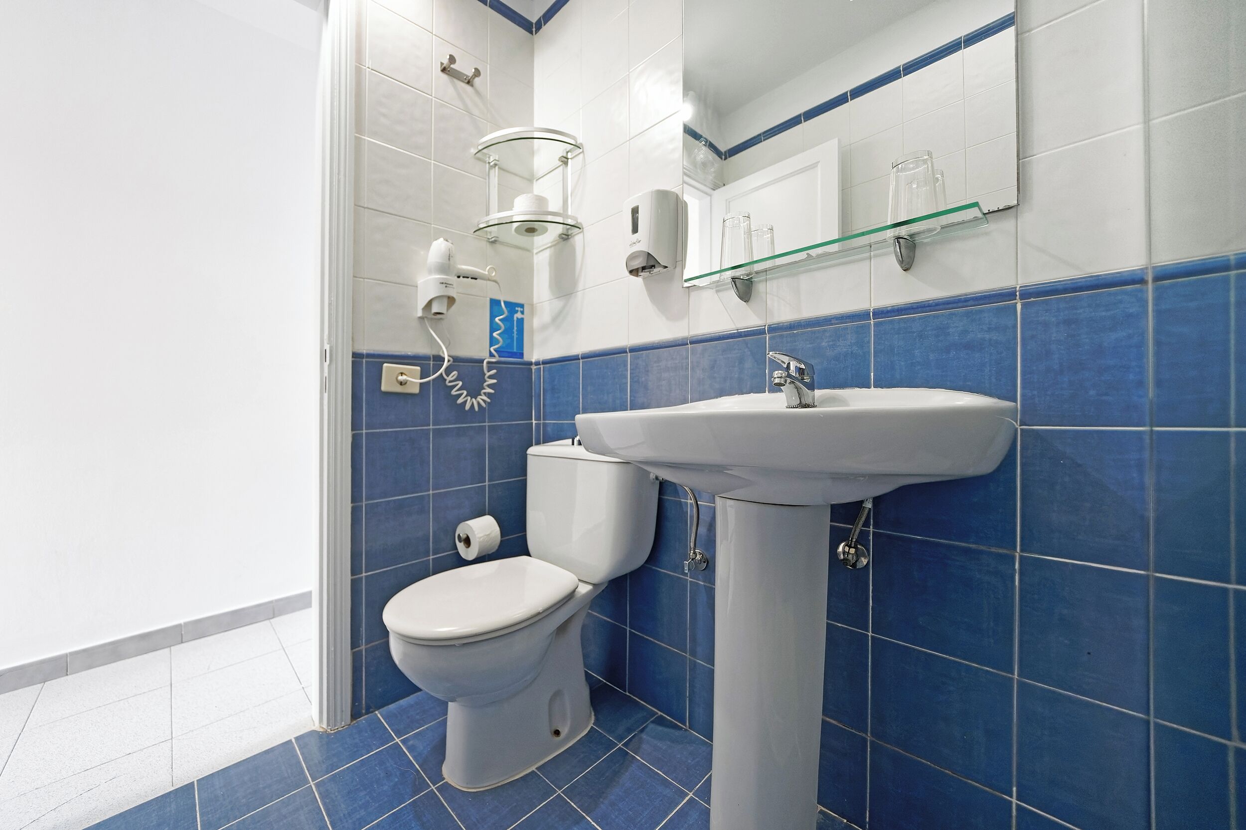 Une salle de bain avec des toilettes, un lavabo et une étagère en verre.