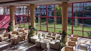 Un vaste espace intérieur aménagé avec différents coins salon et de grandes fenêtres donnant sur l’extérieur.