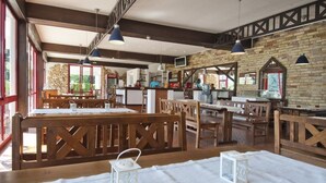Un restaurant avec des meubles en bois, de grandes fenêtres et un mur en briques.
