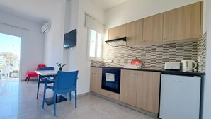 A modern kitchen with wooden cabinets, a built-in oven, and a small refrigerator. - Florence (Ayia Napa)