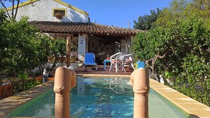 A pool with a tiled deck, surrounded by greenery and a building with a tiled roof. - Zagara di Sicilia (Marsala)
