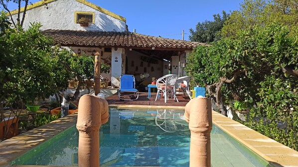 A pool with a tiled deck, surrounded by greenery and a building with a tiled roof. - Zagara di Sicilia (Marsala)
