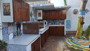 A compact kitchen with wooden cabinets, a microwave, and a tiled backsplash. - Zagara di Sicilia (Marsala)