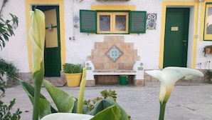 A building with a stone fireplace, green shutters, and a bench in front. - Zagara di Sicilia (Marsala)