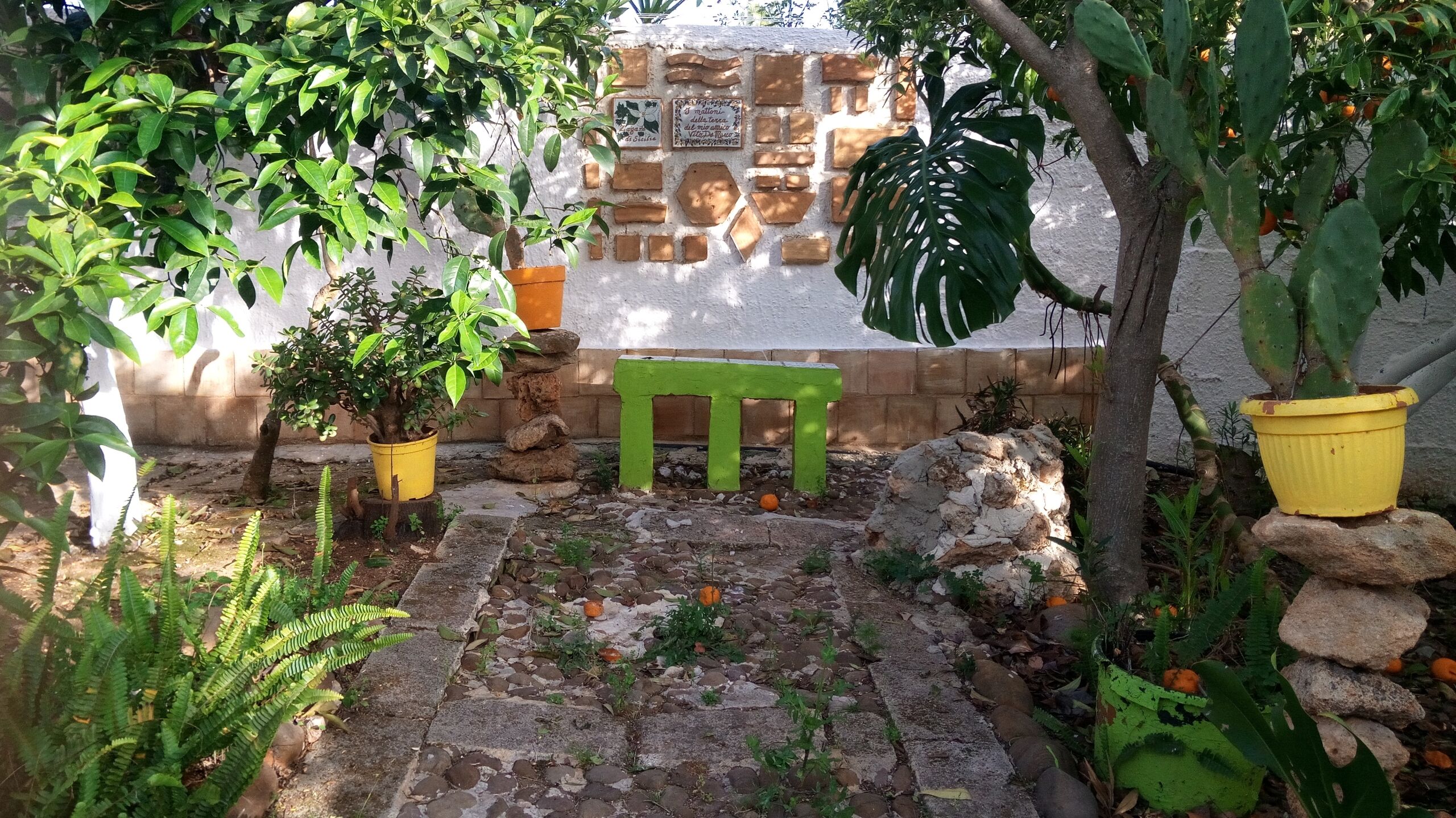 A garden with a stone pathway, a green bench, and potted plants.