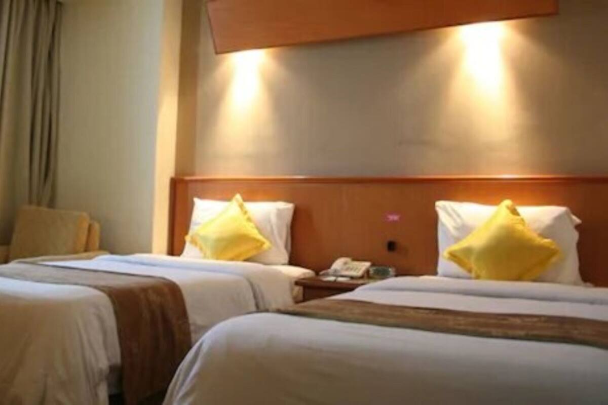Ein Hotelzimmer mit zwei Betten, jeweils mit Holz Kopfteil und Nachttisch.