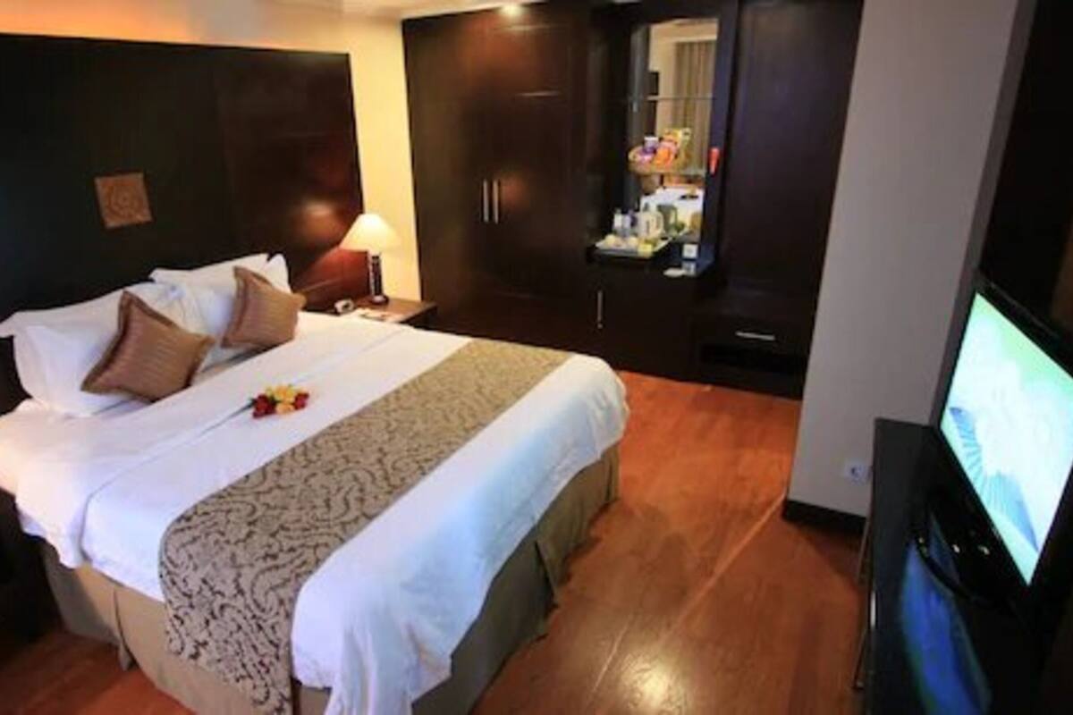 Ein Hotelzimmer mit einem großen Bett, einem Fernseher, einem Kleiderschrank und einem Schreibtisch.
