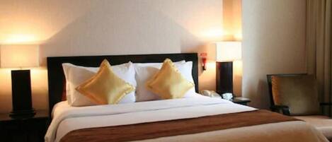 A hotel room with a large bed, two bedside lamps, and a nightstand.
