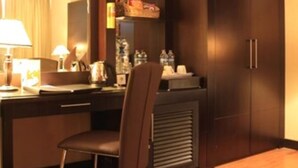 A hotel room with a wooden desk, a chair, a mirror, a minibar, and a trash can. - Hotel Pacific Balikpapan (Balikpapan)