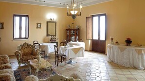 A dining room with a chandelier, ornate chairs, and a table set for a meal. - Palazzo Madeo - Residenza d'Epoca (Crosia)