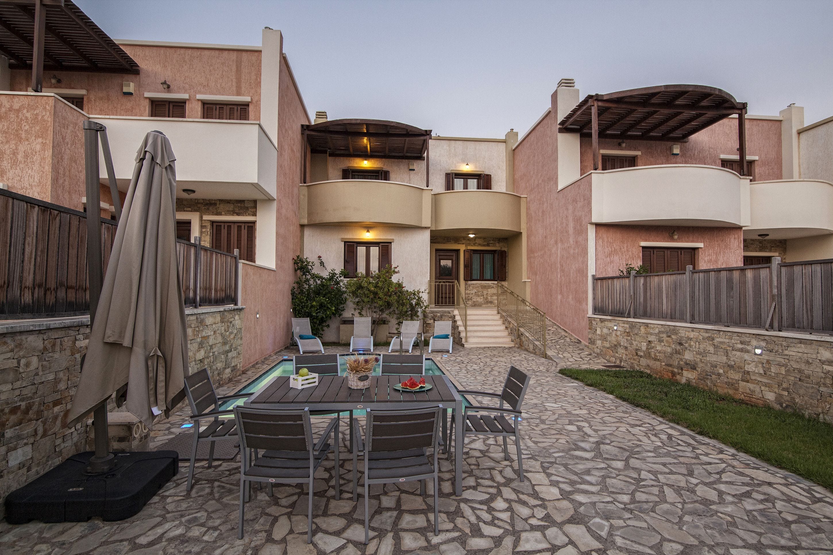 Un patio con suelo de piedra, mobiliario exterior y una zona cubierta.