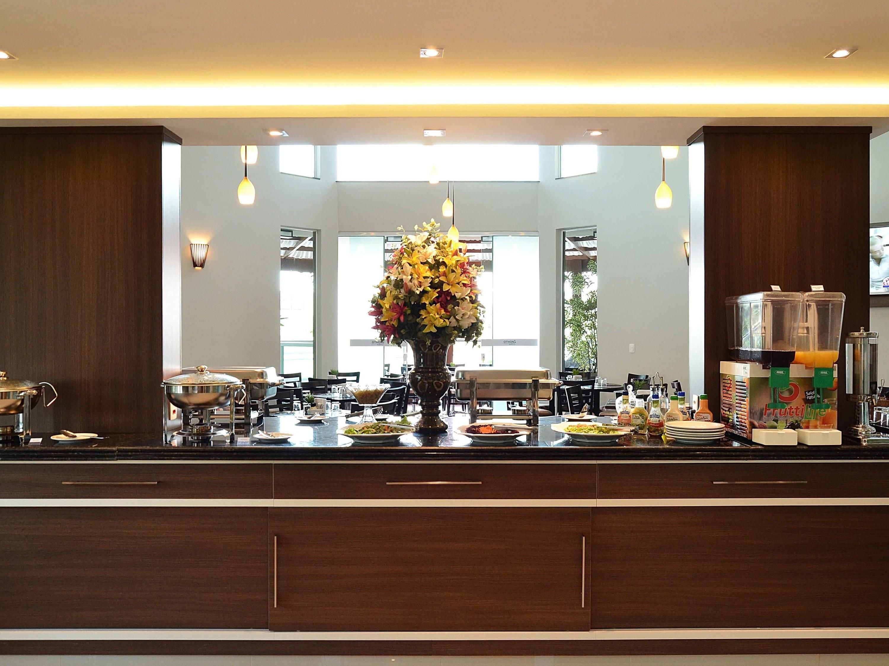 Una cocina moderna con una isla central, un jarrón grande de flores y un dispensador de zumo de frutas.