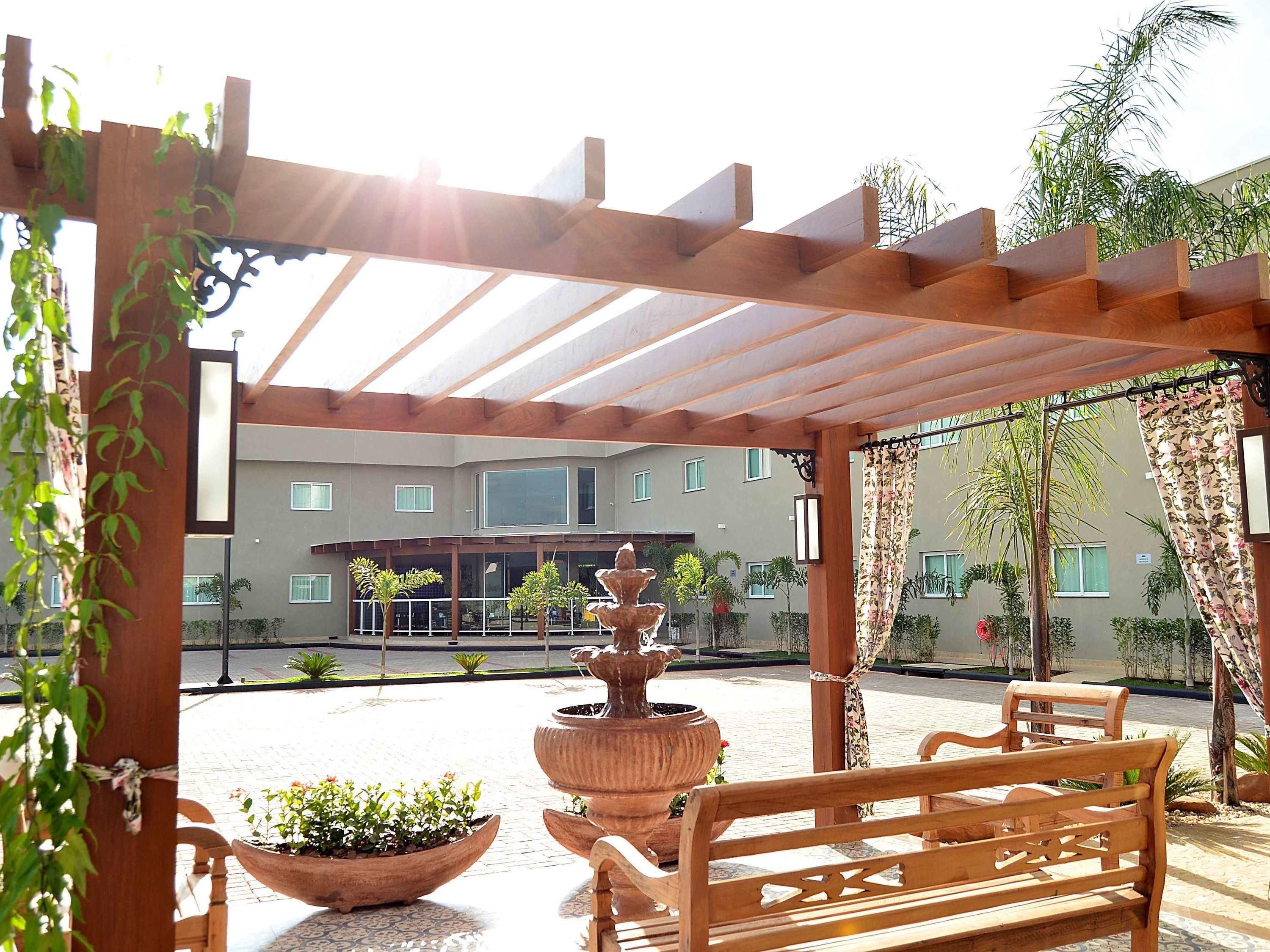 Un espacio al aire libre techado con un banco de madera, una fuente escalonada y plantas en macetas.