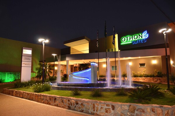 Un hotel con una fuente, un letrero de Othon Suites y una entrada bien iluminada.