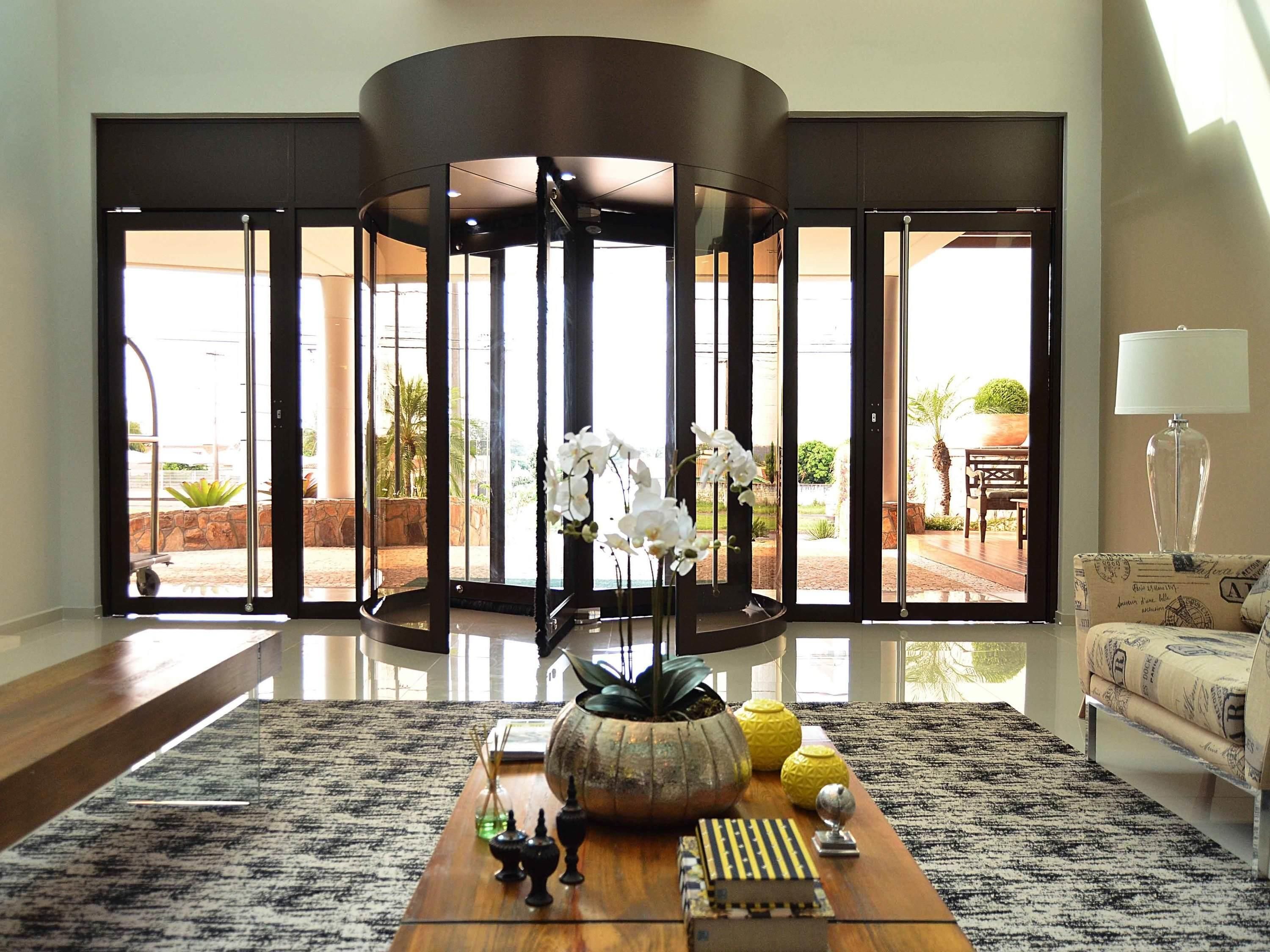Uma sala de estar espaçosa com uma grande porta de vidro que dá para uma área externa, uma mesa de centro de madeira com objetos decorativos e uma luminária moderna.
