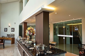 Un hall d’hôtel moderne avec un buffet, un escalier et un mur en verre.