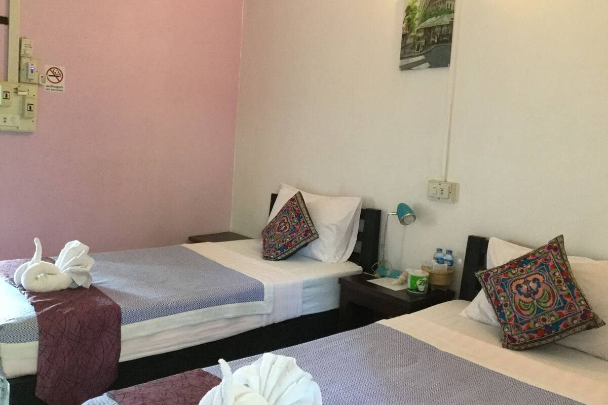 Ein Hotelzimmer mit zwei Einzelbetten, einem Nachttisch mit Lampe, einem Wandbild und einem Rauchverbot-Schild.