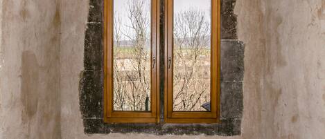 Una habitación con un arco de piedra, suelo de madera y una ventana con vistas a árboles.