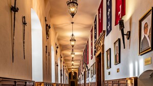 A long hallway with wooden pews, red carpet, and hanging banners.