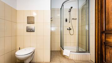 A modern bathroom with a glass-enclosed shower, a toilet, and a wooden door.
