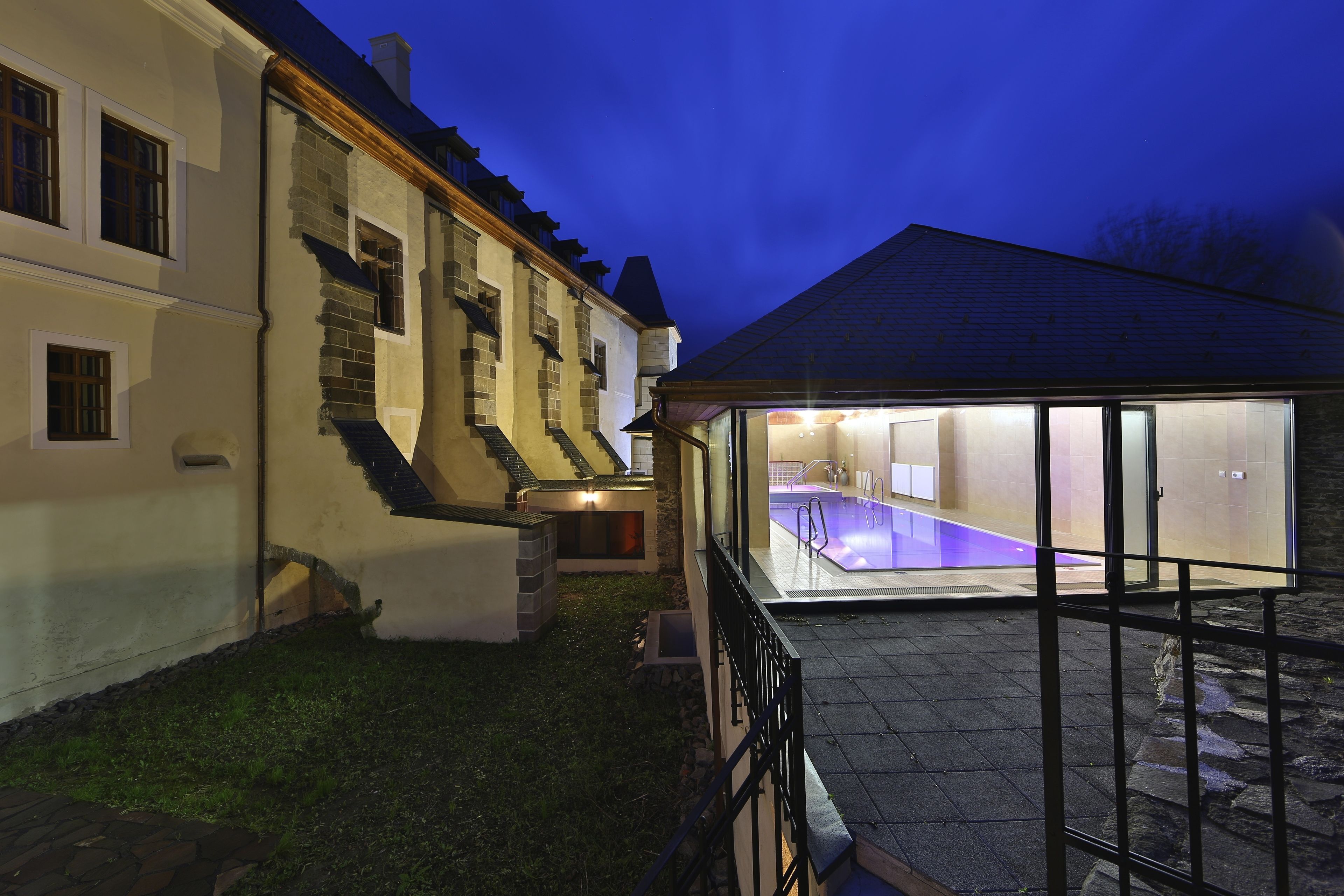 Un bâtiment à deux étages doté d’une piscine, d’un escalier en pierre et d’un patio vitré.
