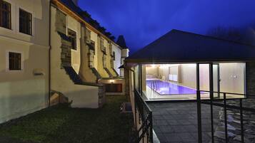 Un bâtiment à deux étages doté d’une piscine, d’un escalier en pierre et d’un patio vitré.