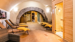 A spa area with stone arches, wooden walls, and sun loungers with yellow towels.