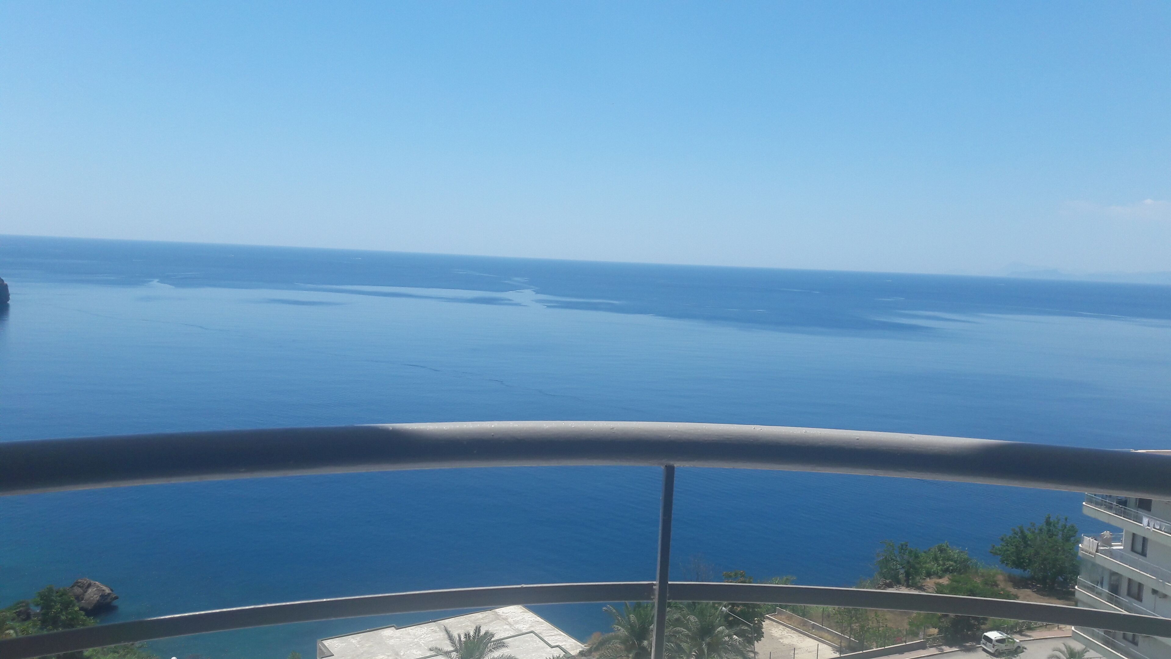 Un balcón con vista al mar y un edificio al fondo.