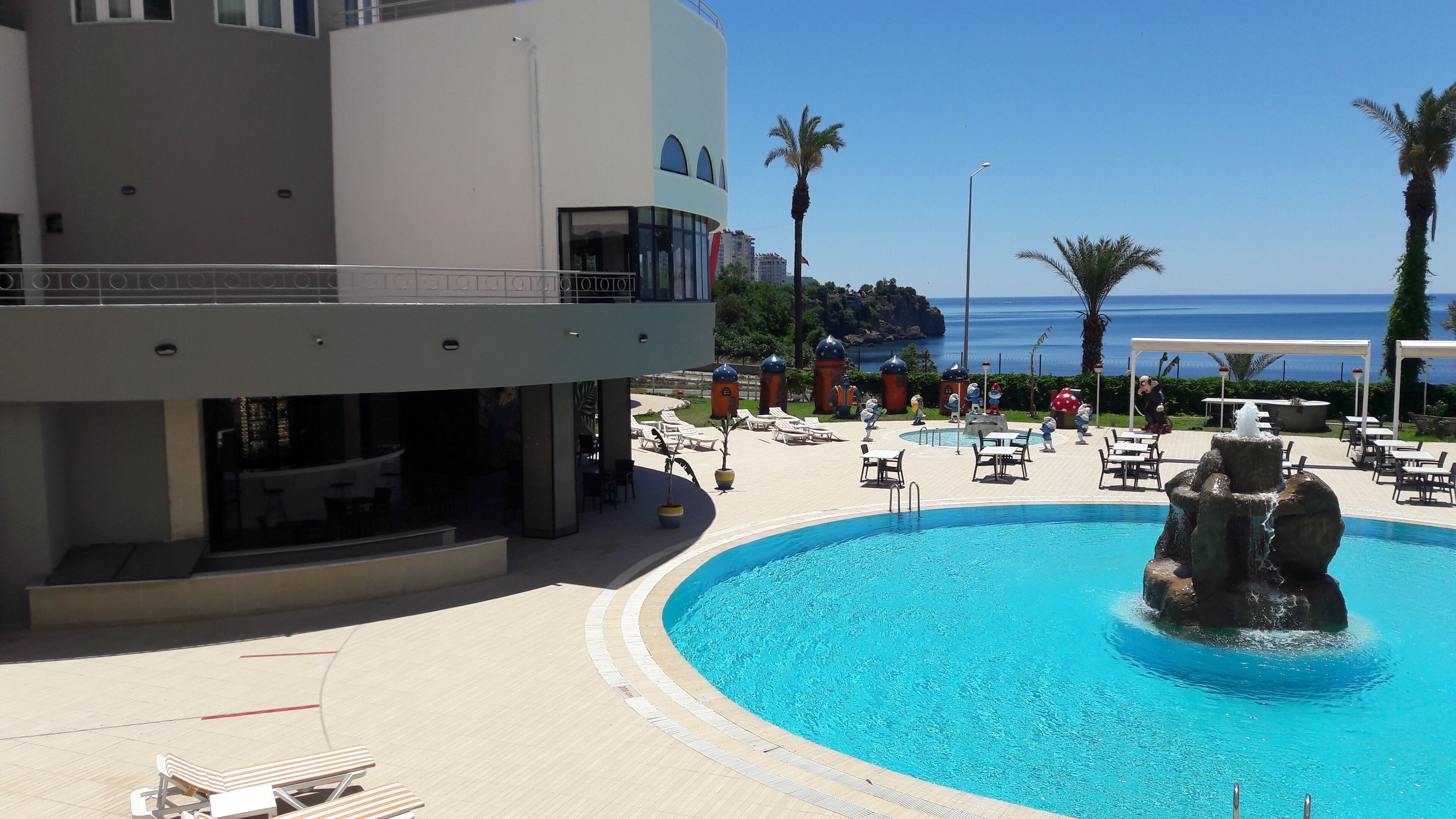 A resort pool with a water feature, lounge chairs, and a view of the sea.