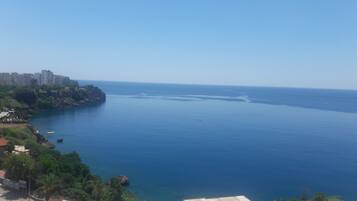A coastal view with a clear sky, a calm sea, and a rocky coastline with buildings.