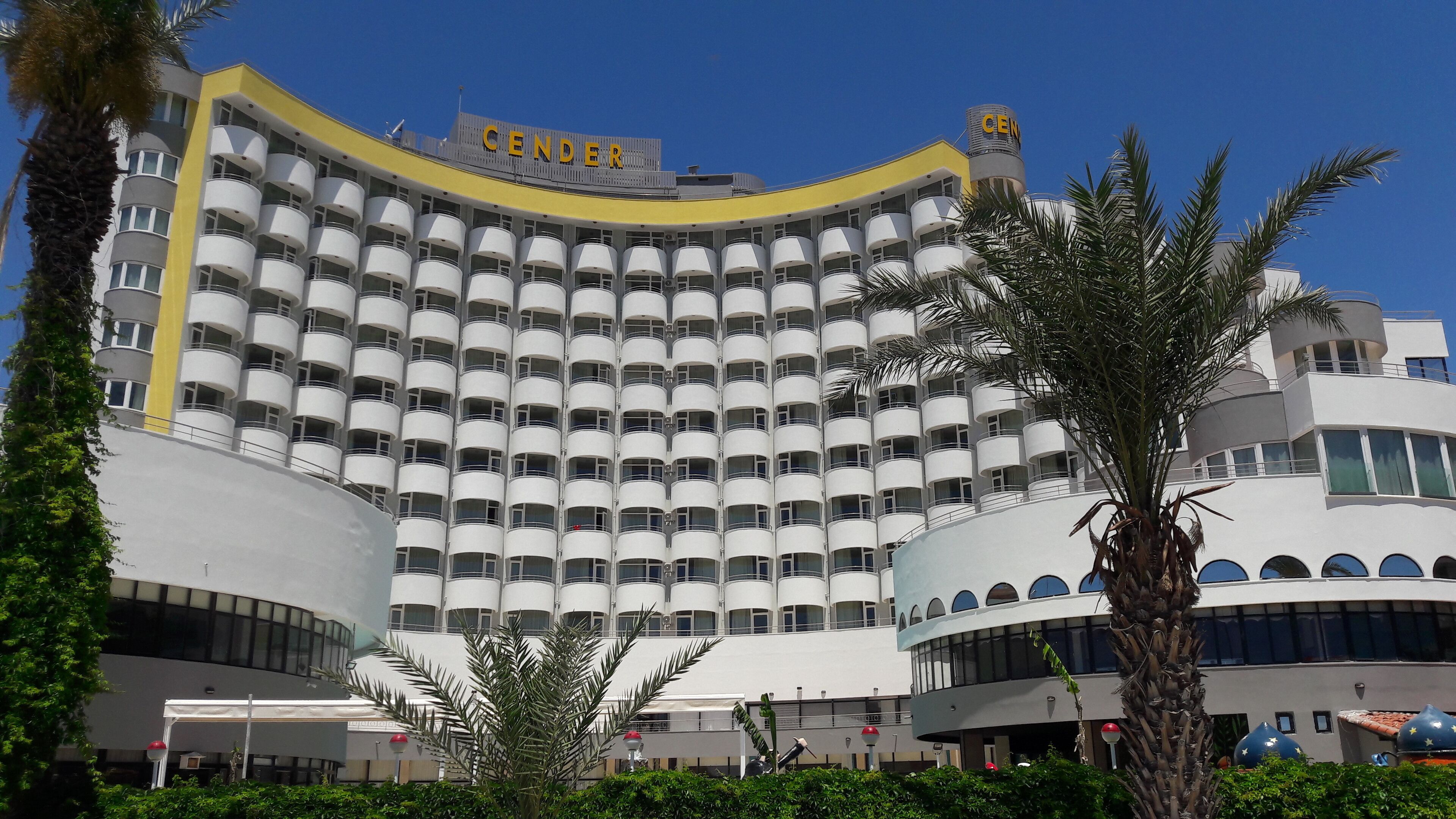 A large, multi-story hotel with a curved facade, numerous balconies, and a prominent 'CENDER' sign.