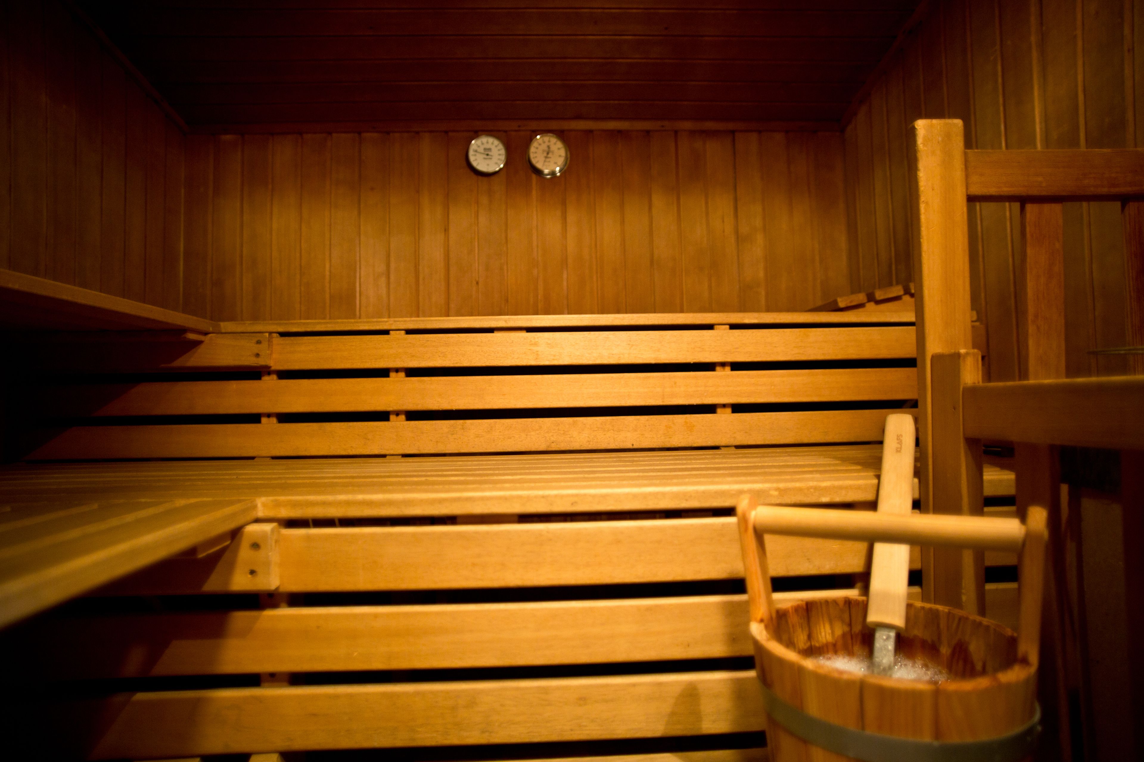 Un sauna avec des bancs en bois et un seau en bois.