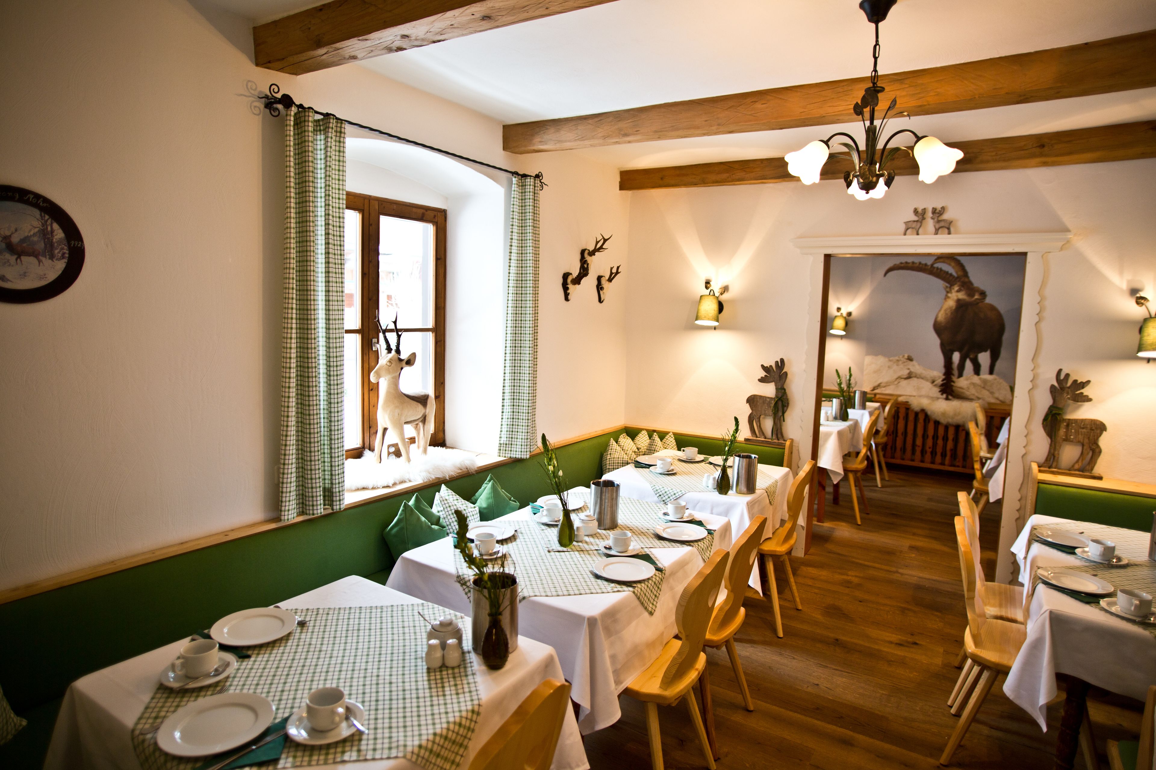 A dining area with checkered tablecloths, wooden chairs, and a green cushioned bench.