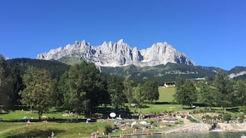 Un resort sul lago con montagne sullo sfondo, dotato di area nuoto e parco con prato.