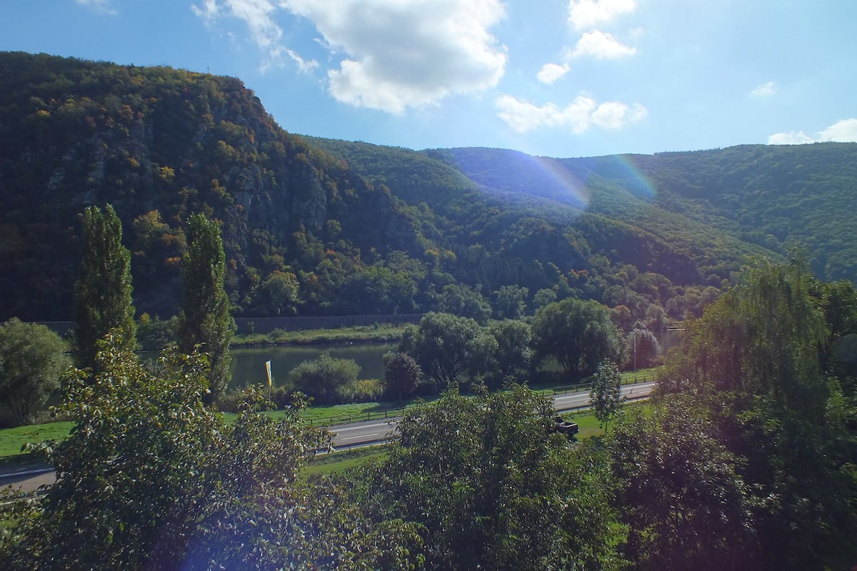 A landscape with a road, trees, and hills.
