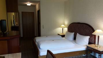 Ein Hotelzimmer mit Bett, Nachttischen, Schreibtisch, Stuhl, Fernseher und einer Tür.