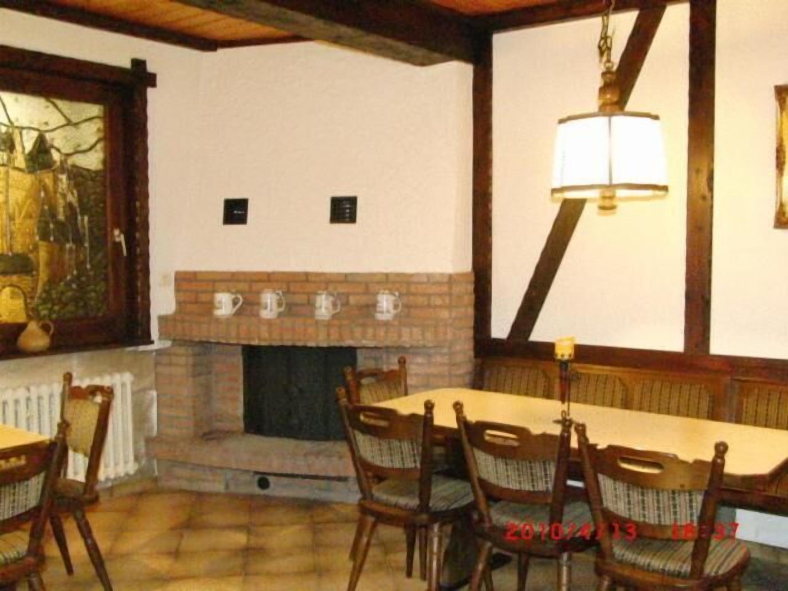Uma sala de jantar com lareira de tijolos, cadeiras de madeira e uma mesa.