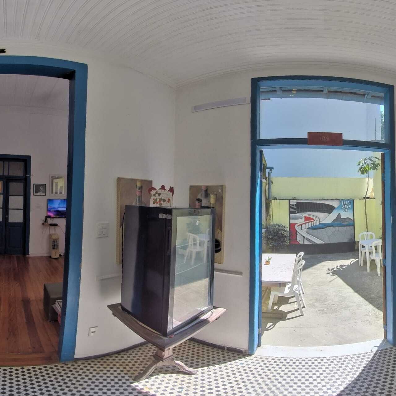 A room with a television on a stand, a door leading to a balcony, and a view of a building with a mural.