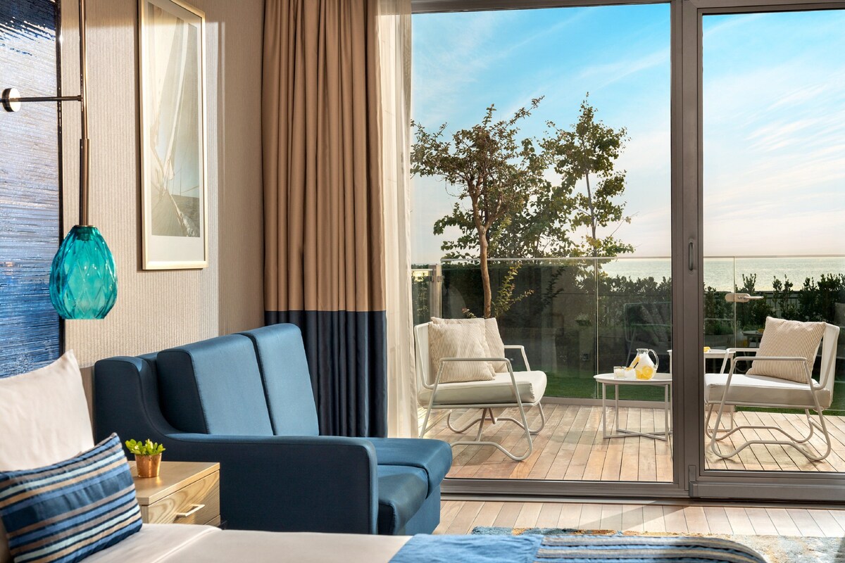 Ein modernes Hotelzimmer mit einer großen Glasschiebetür, die auf eine Terrassenanlage führt.