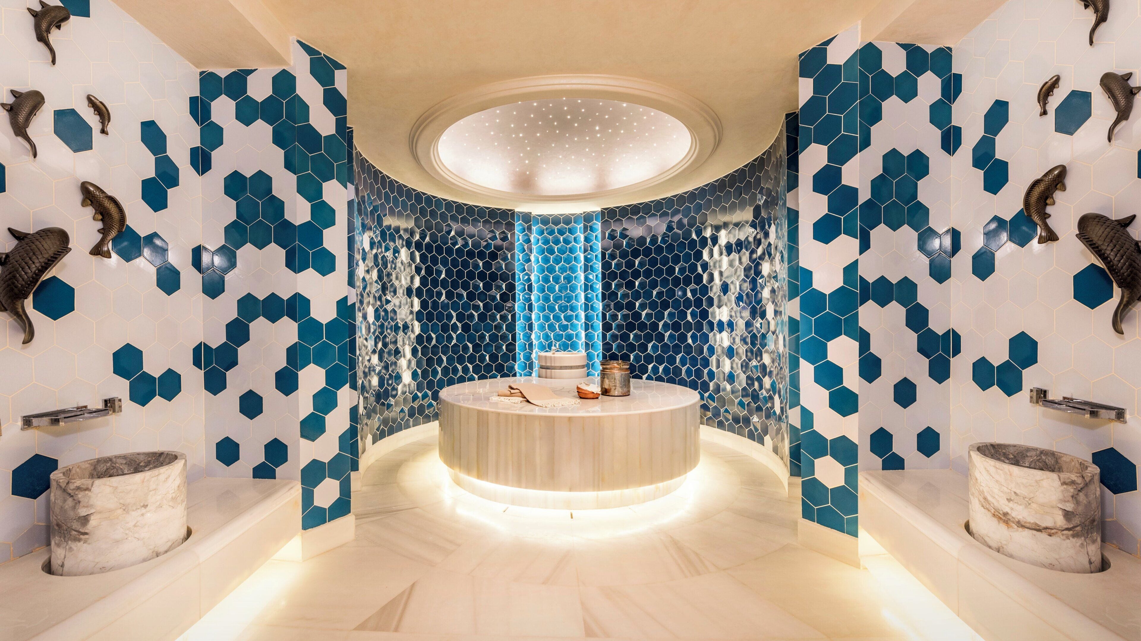 A modern bathroom with a circular sink, blue hexagonal tiles, and decorative fish.