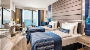 Una habitación de hotel moderna con dos camas, un escritorio y vista al mar.