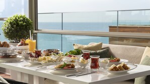 A breakfast table with various dishes and drinks, overlooking a scenic ocean view. - Crowne Plaza Istanbul Florya by IHG (Istanbul)