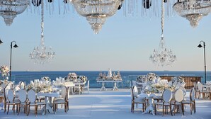 An outdoor wedding venue with tables set for guests, chandeliers, and a view of the ocean. - Crowne Plaza Istanbul Florya by IHG (Istanbul)