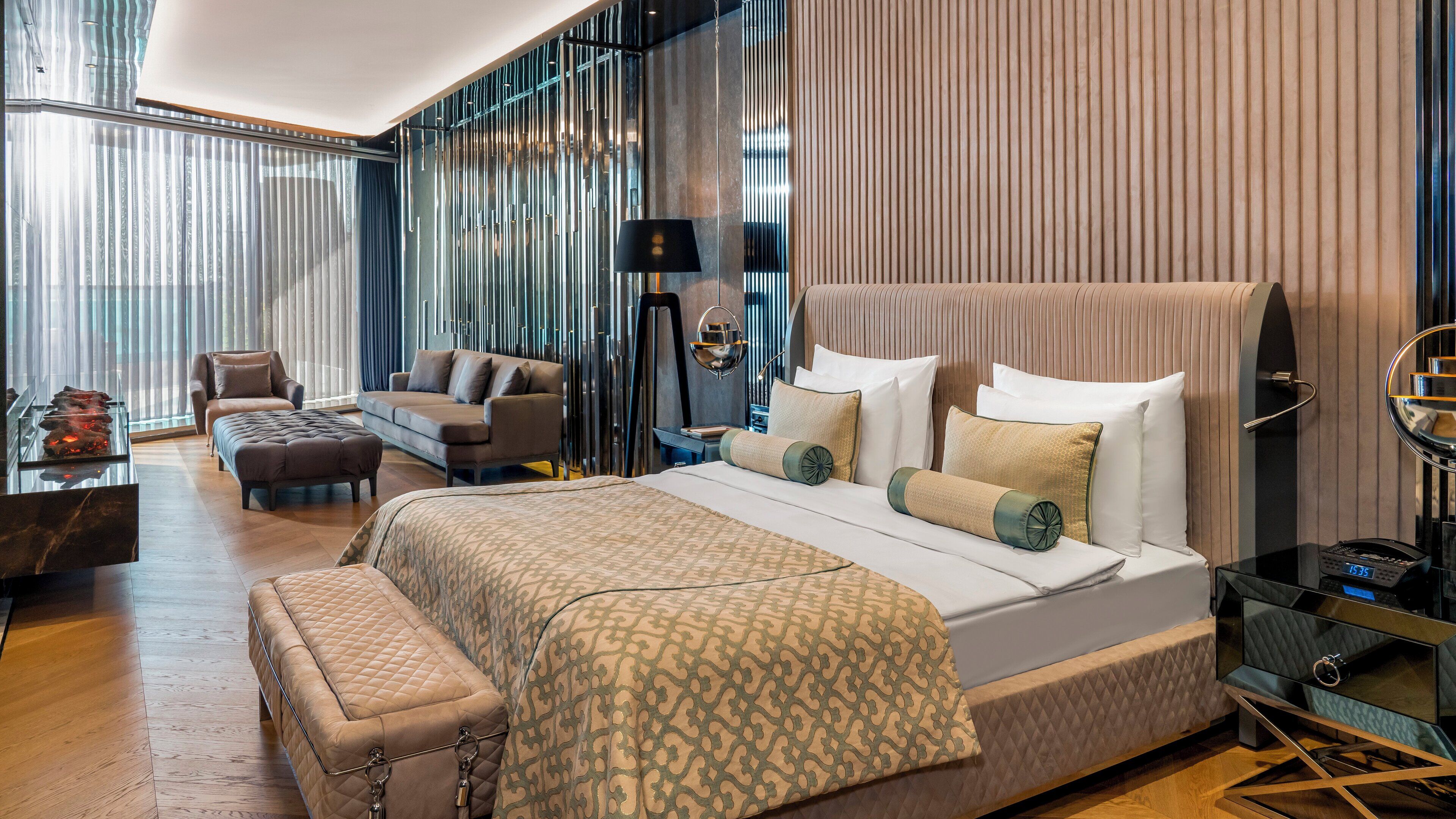 Una habitación de hotel moderna con una cama grande, un sofá, un escritorio y un ventanal con persianas.