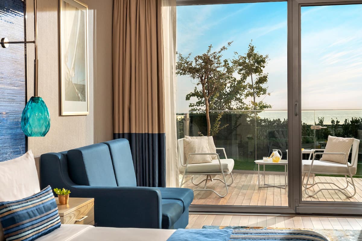 A modern hotel room with a large sliding glass door leading to an outdoor deck.