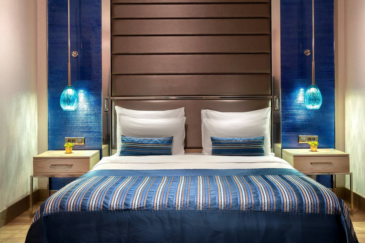 A modern hotel room with a large bed, two bedside tables, and decorative wall sconces.