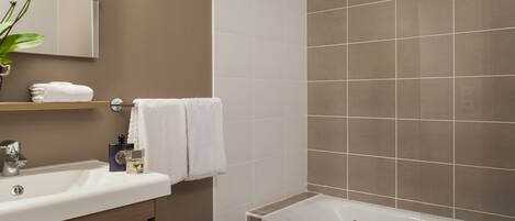 A bathroom with a sink, mirror, and bathtub.