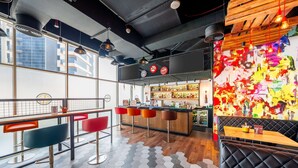Eine moderne Bar mit sechseckischem Fliesenspiegel, Barhocker und farbenfroher abstrakter Wandkunst.