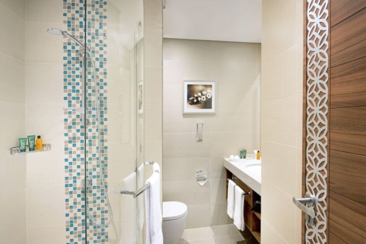 Een moderne badkamer met douche, toilet en wastafel.