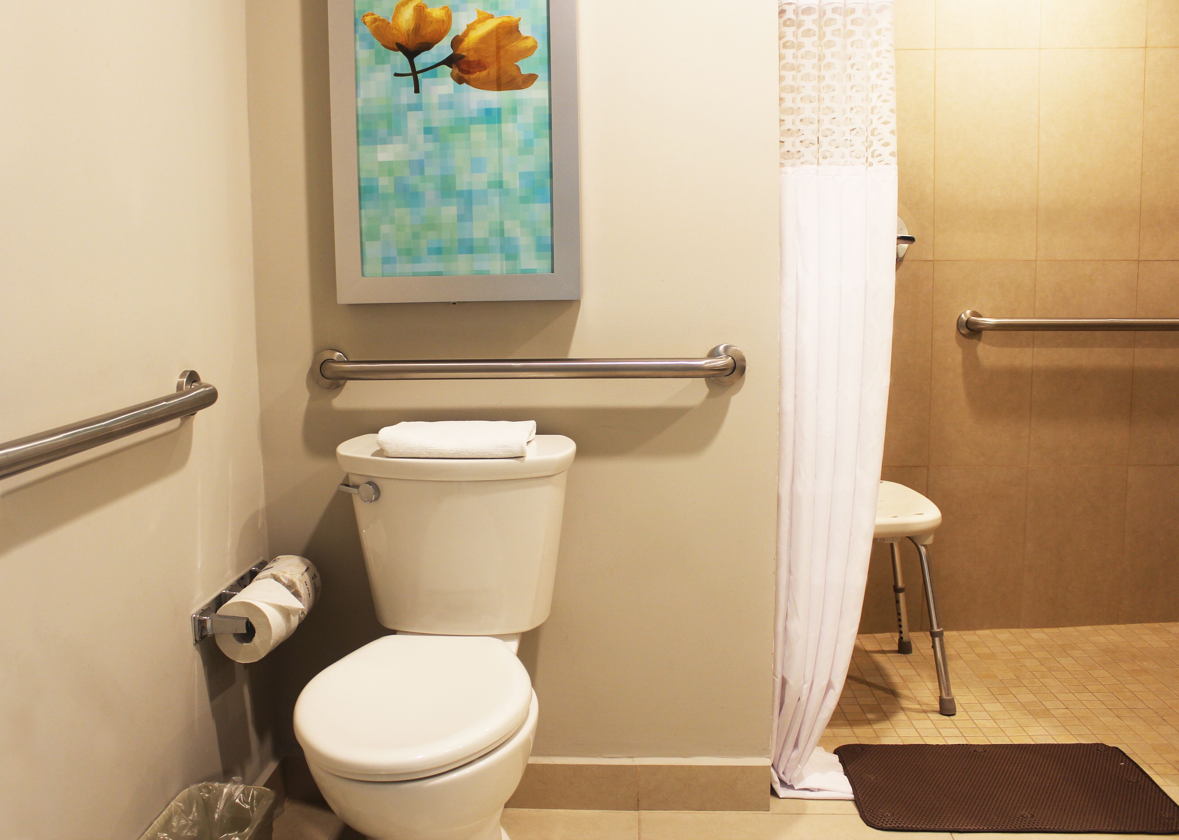 Un baño con inodoro, baranda, cortina de ducha y un cuadro de hojas.